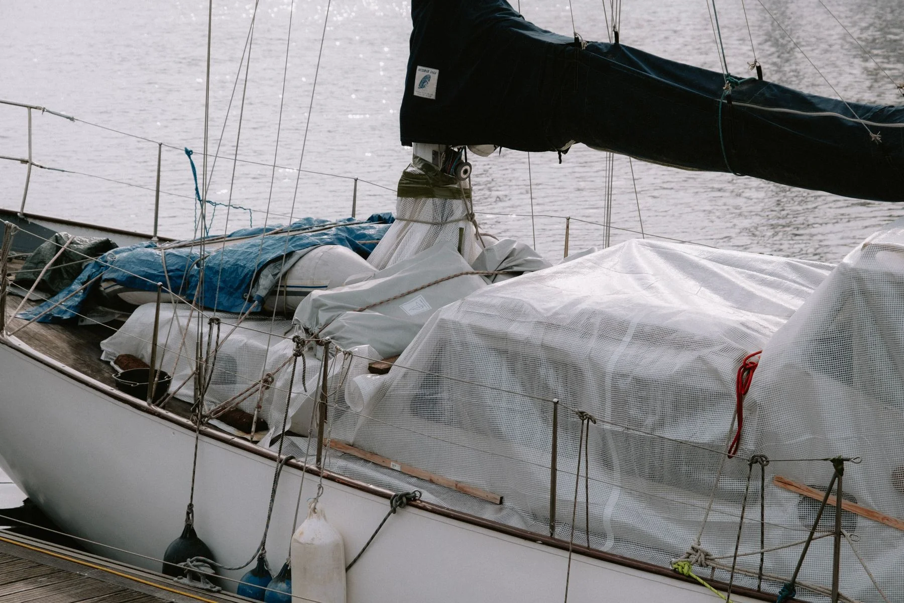 Sailboat covered at a marina with mooring lines.