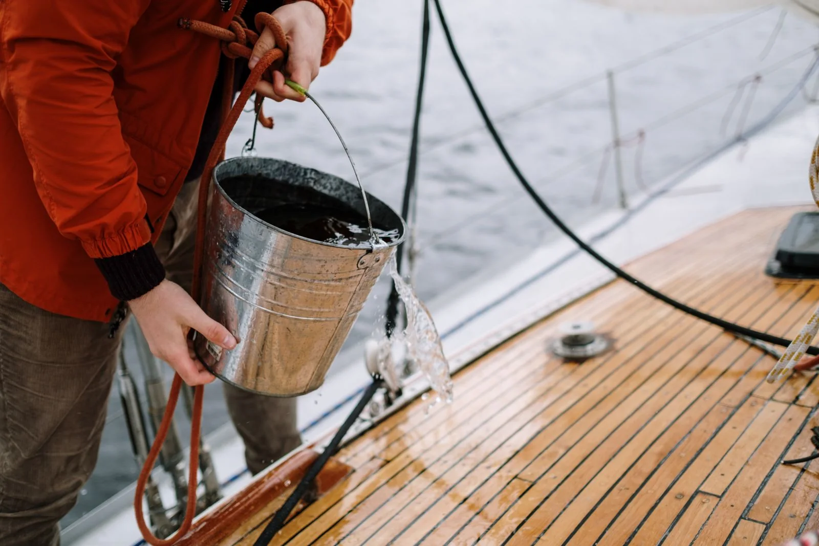 Cleaner scrubbing a teak boat deck by hand.