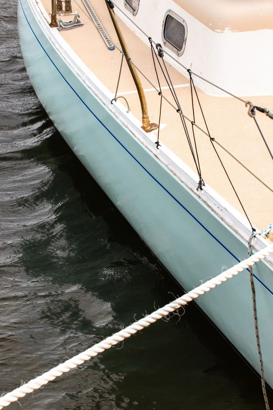 Boat hull and rigging beside the water.