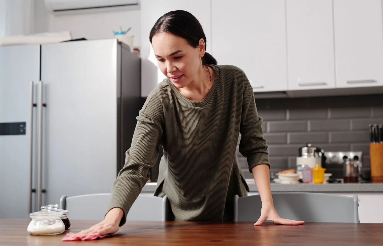 Person wiping a kitchen table.