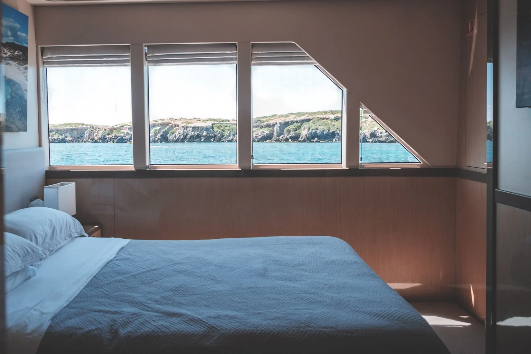 Fresh bedding in a yacht cabin with a sea view.