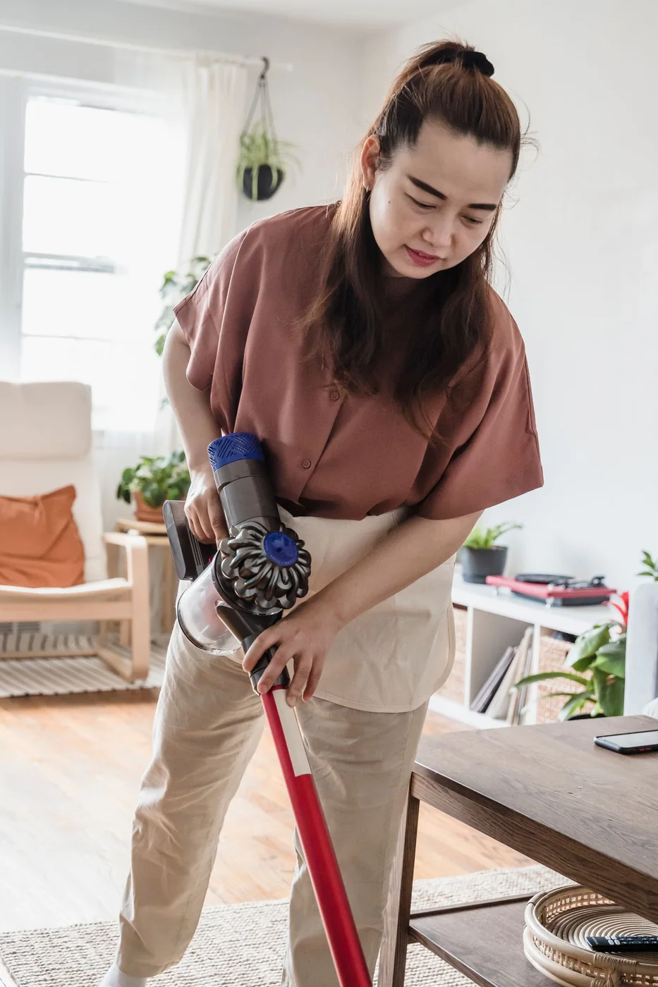 Person vacuuming a bright living room.