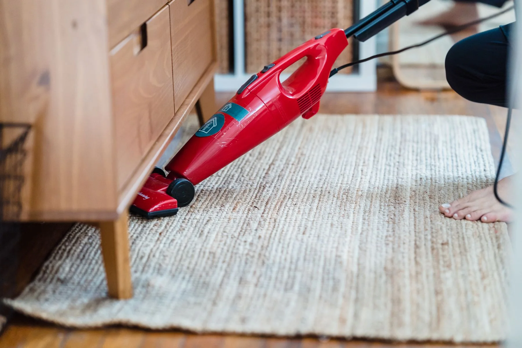 Vacuum cleaner on a carpet beneath furniture.