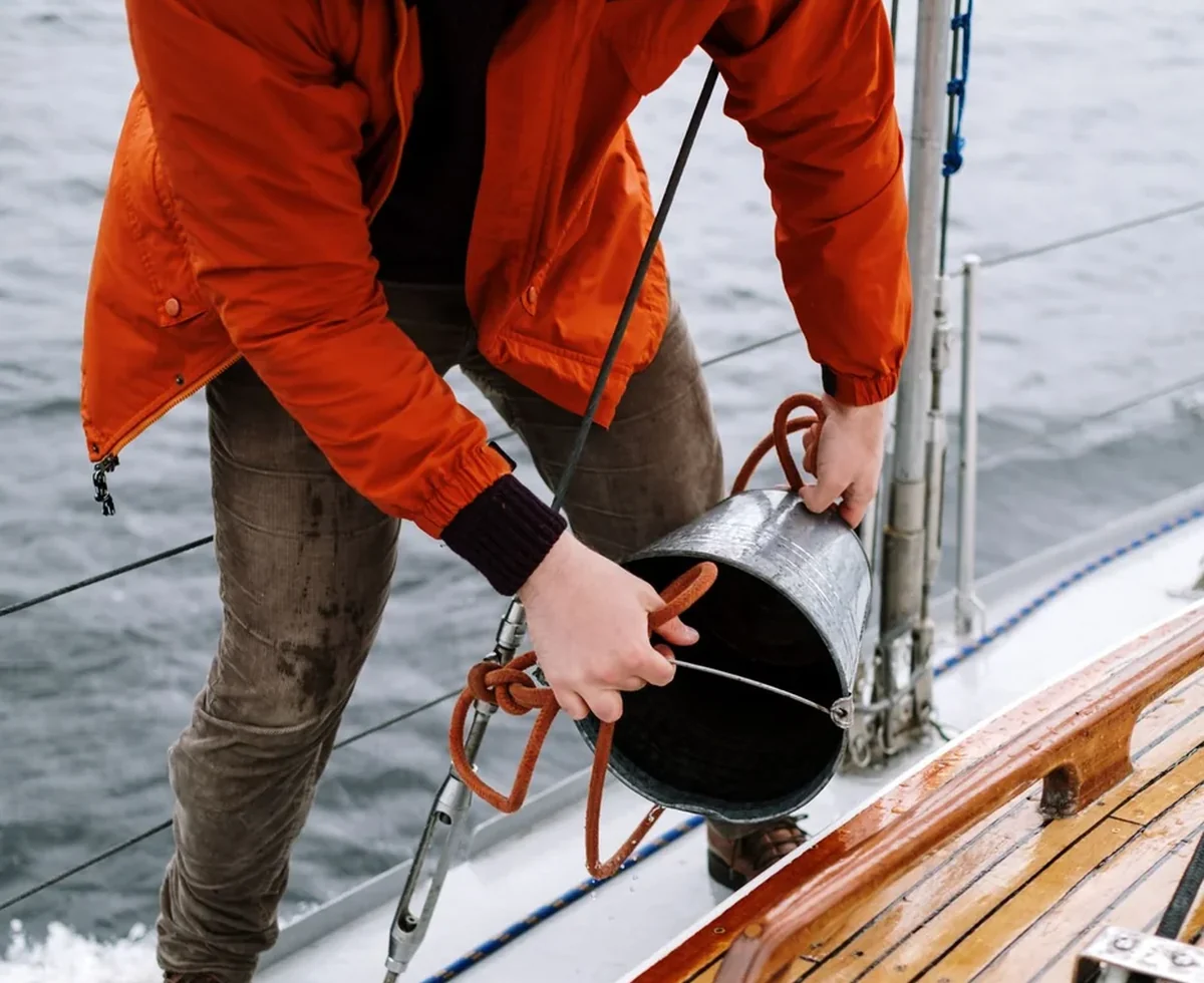 Worker cleaning a teak yacht deck by hand.